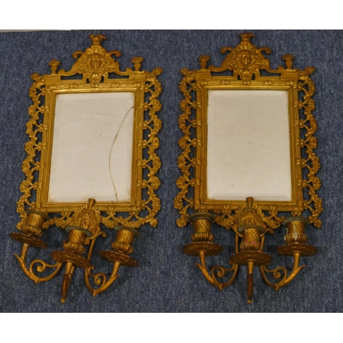 904 - A pair of gilt metal hanging bevelled mirrored wall sconces with allover embossed and pierced figure... 