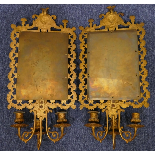 904 - A pair of gilt metal hanging bevelled mirrored wall sconces with allover embossed and pierced figure... 