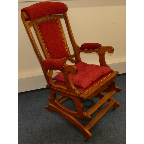 960 - An oak American rocking chair with red overstuffed and studded seat and back with padded arms, on ca... 