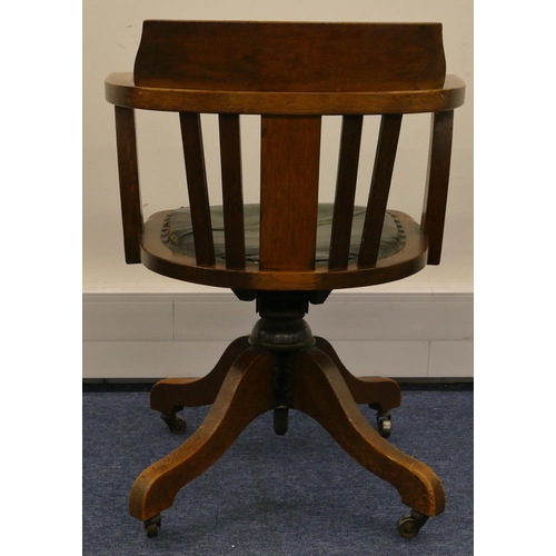 962 - A 1930's oak swivel tub desk chair with slat back, leather studded overstuffed seat (in need of rest... 