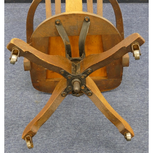 962 - A 1930's oak swivel tub desk chair with slat back, leather studded overstuffed seat (in need of rest... 