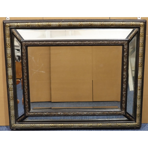 978 - A 19th Century Flemish ebony and brass hanging cushion fronted bevelled wall mirror with embossed fl... 