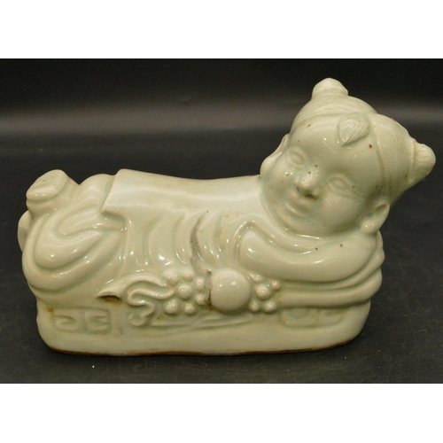 98 - An Oriental glazed earthenware pillow in the form of a child, 22cm long