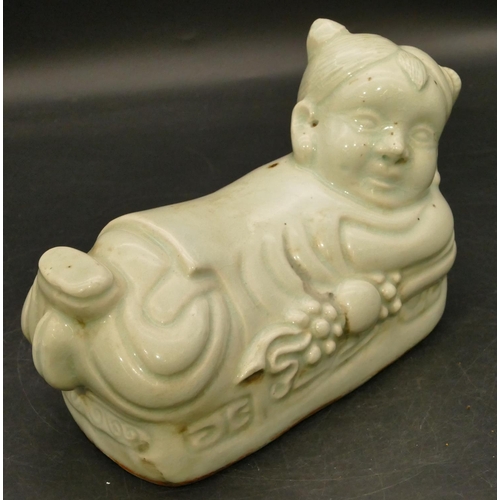 98 - An Oriental glazed earthenware pillow in the form of a child, 22cm long