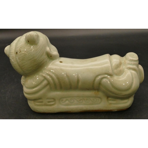 98 - An Oriental glazed earthenware pillow in the form of a child, 22cm long