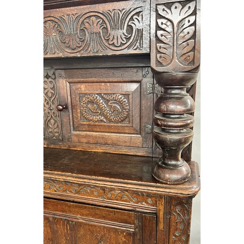 984 - An 18th century oak court cupboard, centre panel flanked by 2 carved panelled doors above 2 large ca... 