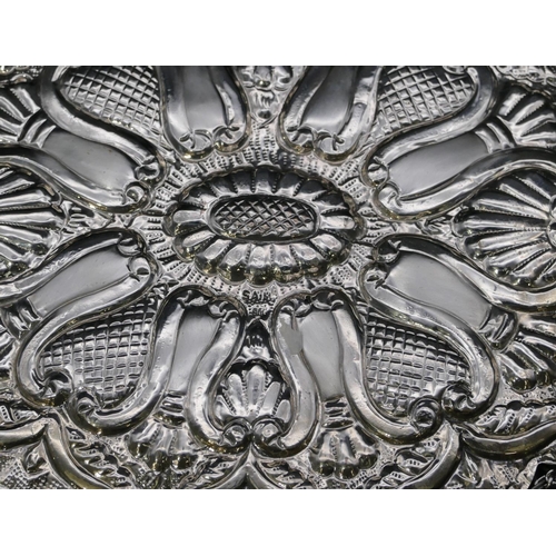 197 - An Eastern silver coloured metal oval scallop shaped hanging mirror with allover embossed decoration... 