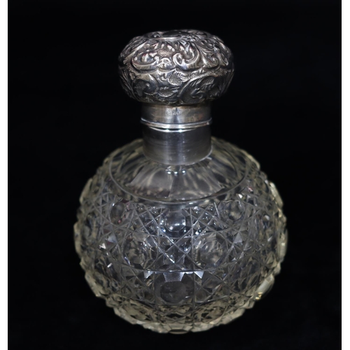 184 - A cut glass round bulbous dressing table bottle with London silver top, embossed with floral and scr... 
