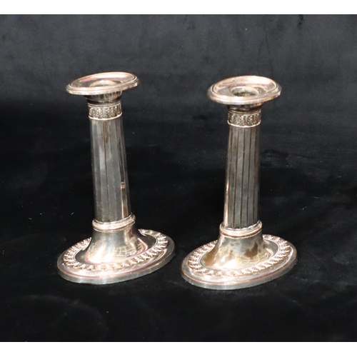 215 - A pair of Sheffield plated oval candlesticks with chamfer decoration, on sweeping bases with leaf de... 