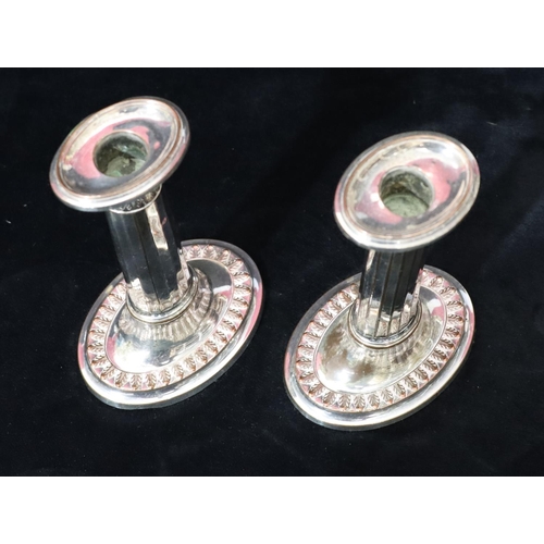 215 - A pair of Sheffield plated oval candlesticks with chamfer decoration, on sweeping bases with leaf de... 