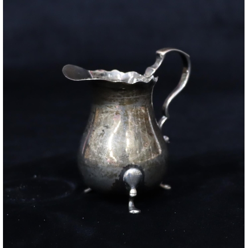 232 - A small silver bulbous shaped cream jug with crinkled rim, scroll handle on splayed feet, 7.5cm high... 