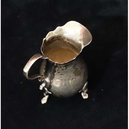 232 - A small silver bulbous shaped cream jug with crinkled rim, scroll handle on splayed feet, 7.5cm high... 