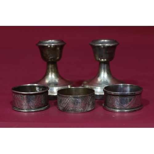 315 - 3 odd silver napkin rings, 2oz, a pair of Chester silver dwarf candlesticks (dented) (5)