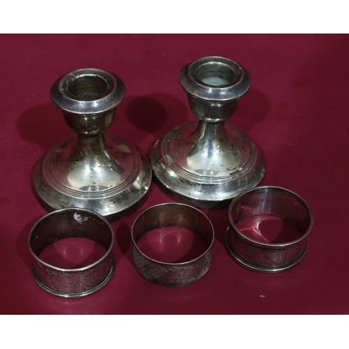 315 - 3 odd silver napkin rings, 2oz, a pair of Chester silver dwarf candlesticks (dented) (5)