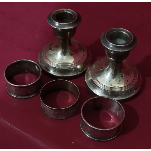 315 - 3 odd silver napkin rings, 2oz, a pair of Chester silver dwarf candlesticks (dented) (5)