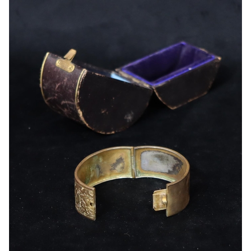 366 - A gilt hinged bangle with chased floral and leaf decoration in leather box