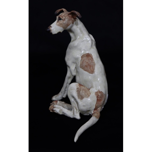 38 - A Studio glazed earthenware figure of a seated dog on white and brown ground, indistinctly stamped w... 