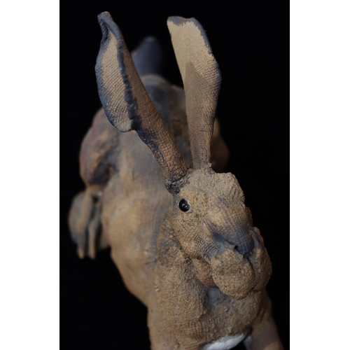 39 - A Studio earthenware figure of a hare with glass eyes (tail restored)