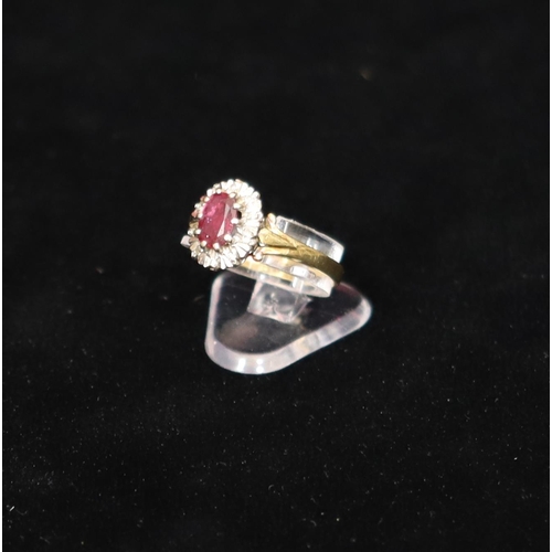 550 - An 18ct gold ladies' cluster ring set with centre oval ruby surrounded by small diamond chips, Size ... 