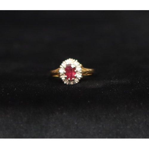 550 - An 18ct gold ladies' cluster ring set with centre oval ruby surrounded by small diamond chips, Size ... 