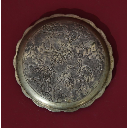 561 - An Oriental silver coloured metal round scallop shaped compact with raised dragon decoration, hinged... 