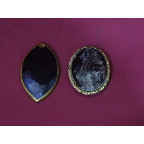 598 - An oval gilt agate style brooch with raised floral and scroll rim (cracked), a similar brooch (2)