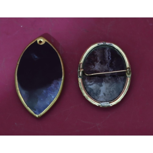 598 - An oval gilt agate style brooch with raised floral and scroll rim (cracked), a similar brooch (2)