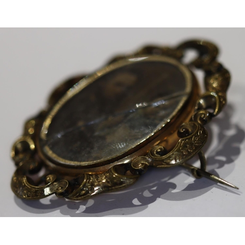 604 - A 19th Century oval swivel mourning brooch with pierced scroll rim, matted hair and portrait of gent... 