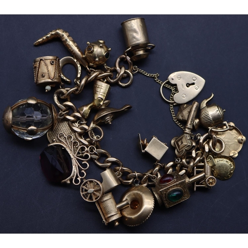 706 - A 9ct gold linked bracelet with padlock clasp, mounted with 20 charms, 100 grams gross