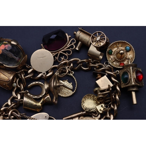 706 - A 9ct gold linked bracelet with padlock clasp, mounted with 20 charms, 100 grams gross