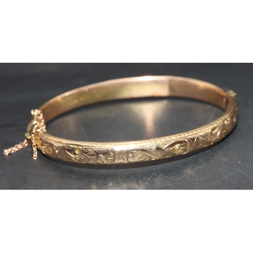 722 - A 9ct gold hinged bangle with embossed floral and leaf decoration (dented), 6.6 grams