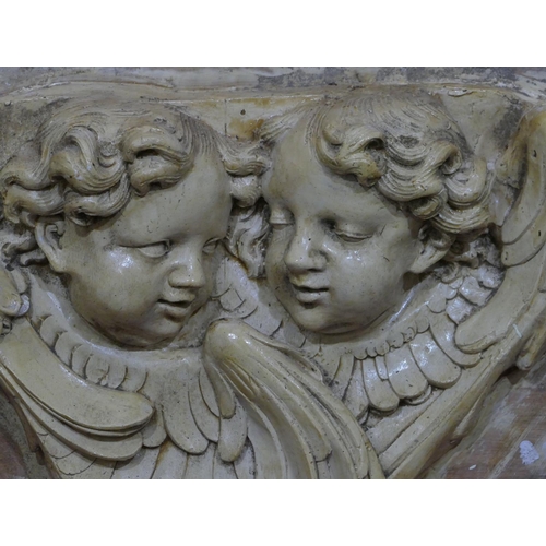 745 - A plaster plaque depicting 2 figureheads of cupids mounted on board, later painted, board 61cm x 74c... 