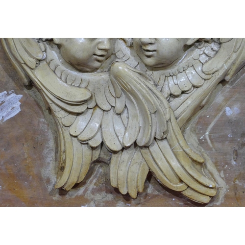 745 - A plaster plaque depicting 2 figureheads of cupids mounted on board, later painted, board 61cm x 74c... 