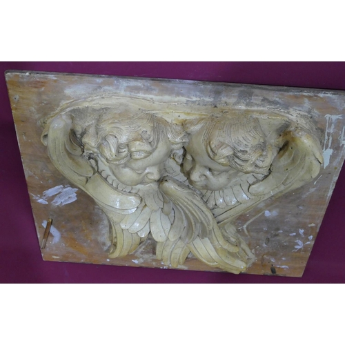 745 - A plaster plaque depicting 2 figureheads of cupids mounted on board, later painted, board 61cm x 74c... 