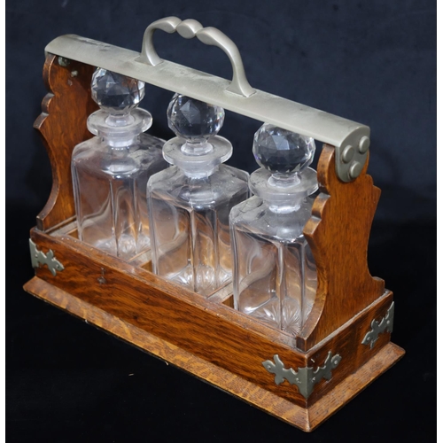 752 - A Victorian oak 3 bottled Tantalus with centre carrying handle, slide out tray containing 3 square d... 