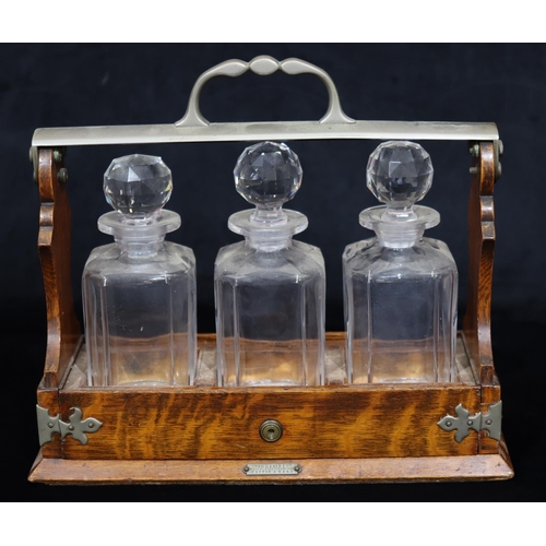 752 - A Victorian oak 3 bottled Tantalus with centre carrying handle, slide out tray containing 3 square d... 