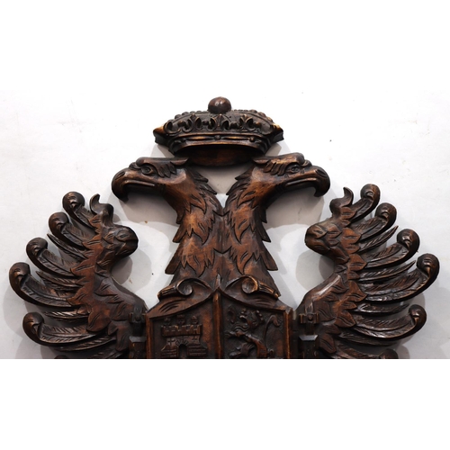 761 - A carved wooden hanging crest with eagle motifs, 84.5cm high, 58cm wide