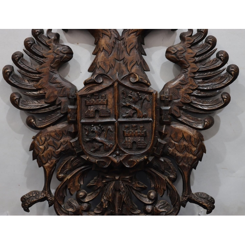 761 - A carved wooden hanging crest with eagle motifs, 84.5cm high, 58cm wide