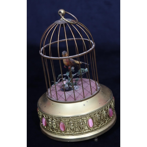 817 - A gilt metal and feathered singing bird in a cage with raised pink carbuncles (1 foot missing and ov... 