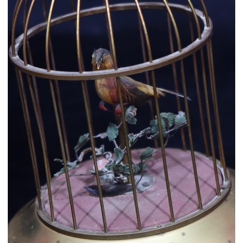 817 - A gilt metal and feathered singing bird in a cage with raised pink carbuncles (1 foot missing and ov... 