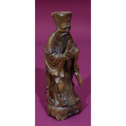 831 - A carved Oriental wooden figure of a standing gentleman, 26cm high