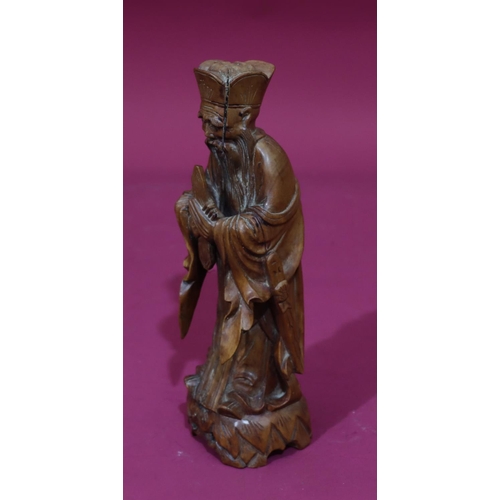 831 - A carved Oriental wooden figure of a standing gentleman, 26cm high