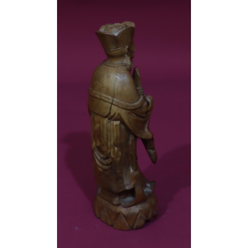 831 - A carved Oriental wooden figure of a standing gentleman, 26cm high