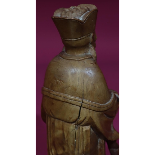 831 - A carved Oriental wooden figure of a standing gentleman, 26cm high