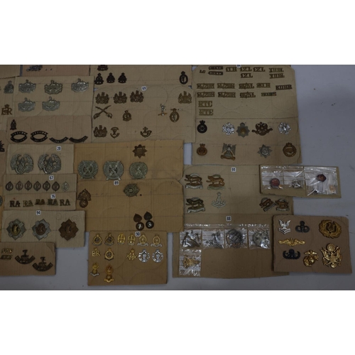 846 - A quantity of various military and other cap badges etc mounted on 26 cut down boards