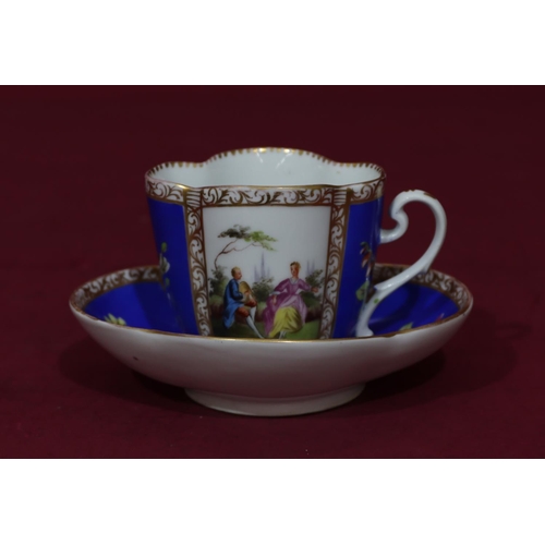 89 - A Dresden oval scallop shaped cup and saucer on white and blue ground with multicoloured figure, flo... 