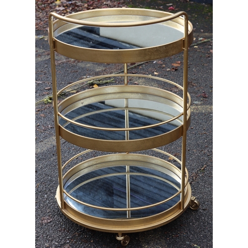 1025 - A retro gilt metal 3-tierd drinks trolley on castors with mirrored shelves, 96cm high overall, 56.5c... 