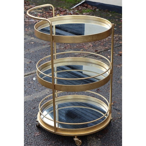 1025 - A retro gilt metal 3-tierd drinks trolley on castors with mirrored shelves, 96cm high overall, 56.5c... 