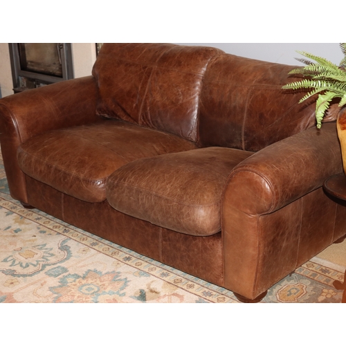 1040 - A brown 2- seater leather sofa, 2 base cushions, 2 back cushions with velcro fittings, on wood bun f... 