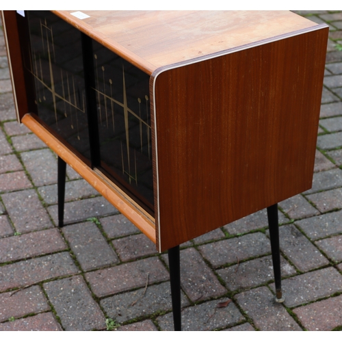 1105 - A 1950's teak low cabinet with black gloss sliding doors. gilt decoration, on round tapering legs, 6... 